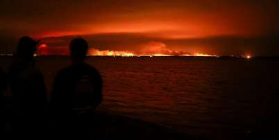 Turistas observam inc&ecirc;ndio florestal atingir uma &aacute;rea de mata pr&oacute;xima &agrave; ba&iacute;a de Arcachon, no oeste da Fran&ccedil;a, em meio ao agravamento da seca ap&oacute;s uma onda de calor e &agrave; escassez de &aacute;gua em grande parte do pa&iacute;s, em 24 de julho de 2026. Foto: REUTERS - Stephane Mahe / RFI