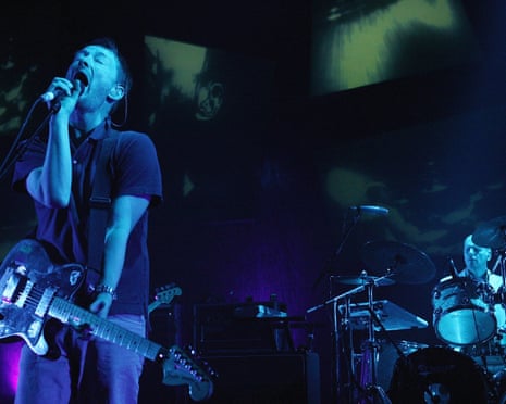Thom Yorke and Philip Selway of Radiohead performing onstage, bathed in blue light
