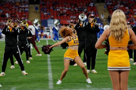 Arizona cheerleaders and marching band on the pitch at halftime.