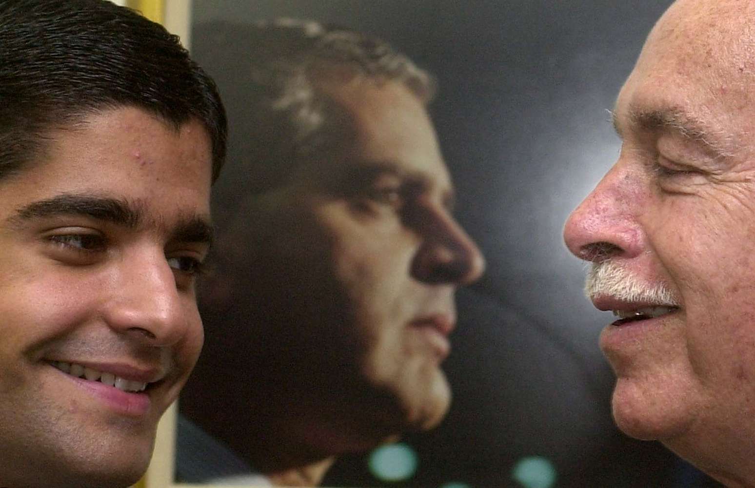 ACM sorri para seu neto ACM Neto no gabinete do tamb&eacute;m senador ACM Filho, em 2002. Ao fundo, foto de Ant&ocirc;nio Carlos Magalh&atilde;es Filho