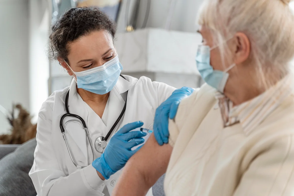 Médico vacinando uma idosa. Metrópoles