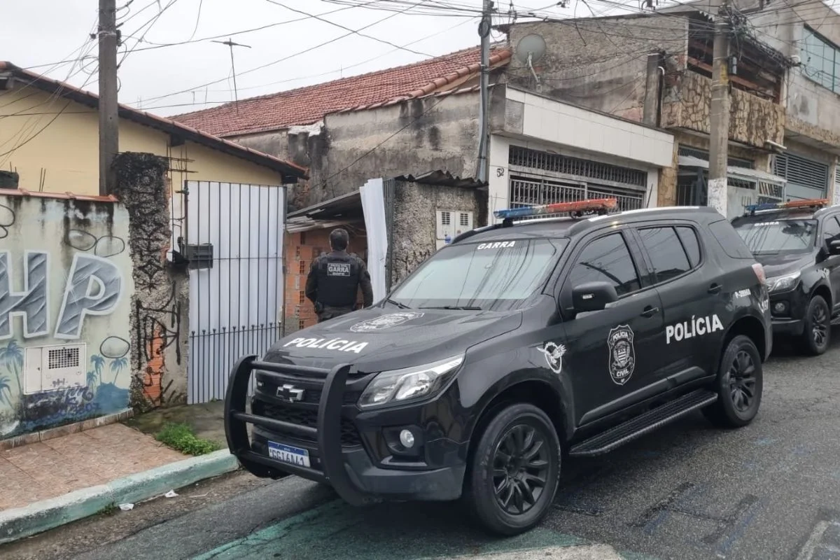 Foto colorida de viatura da Polícia Civil em frente à imóvel alvo de operação contra falsos leilões.
