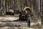 Homem passa perto de máquinas militares russas destruídas na floresta no norte de Kiev, Ucrânia