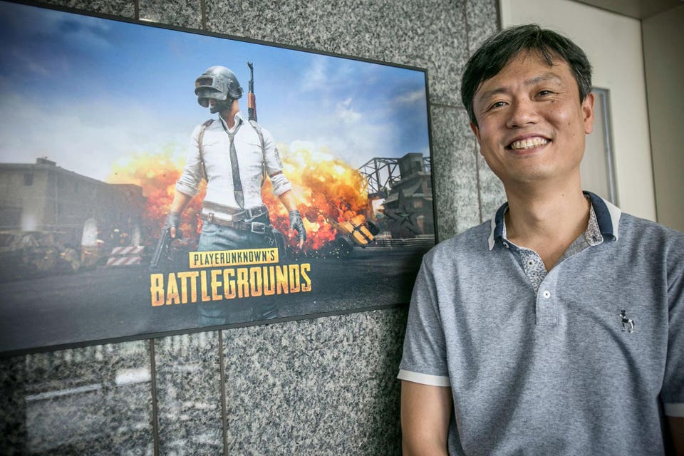 Một người đ&agrave;n &ocirc;ng đứng cạnh m&agrave;n h&igrave;nh hiển thị PUBG: Battlegrounds