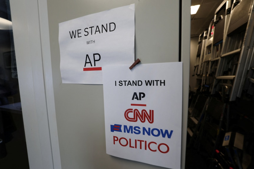 Two paper print outs on a door reading We stand with AP and I stand with AP CNN MS Now POLITICO