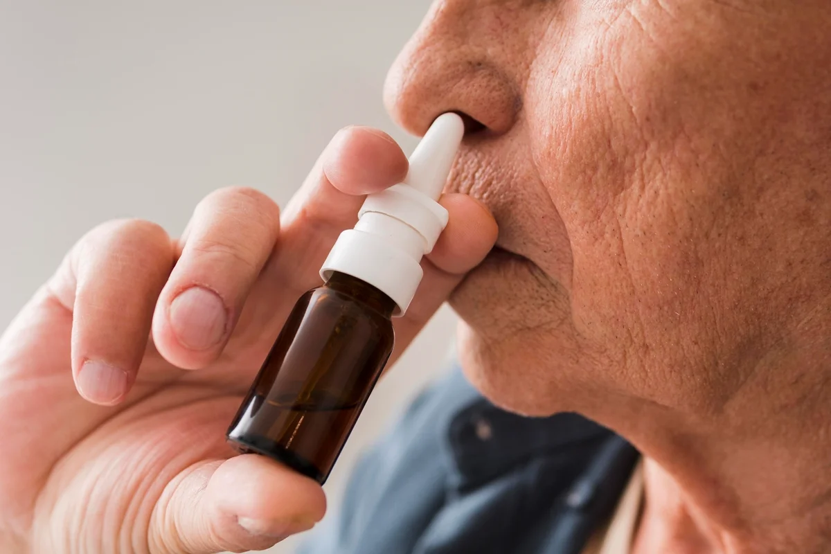 Imagem colorida de um pessoas utilizando spray nasal - Metrópoles
