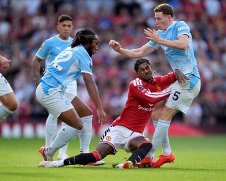 Marcus Rashford falls to the ground as he competes for the ball with Semenyo and Anderson