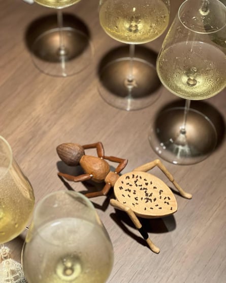 The ants laid out on a wooden ant decoration on a table surrounded by wine glasses