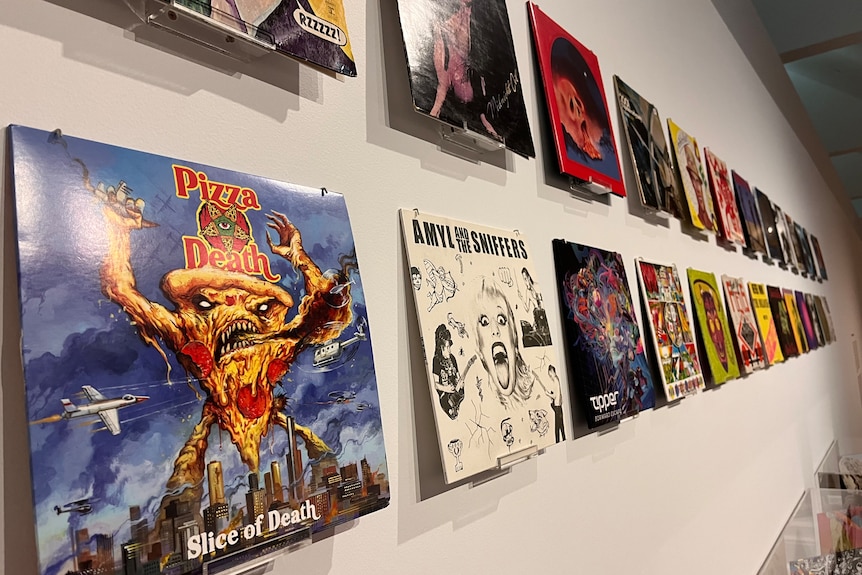 An exhibition of punk vinyls on the wall of a gallery.