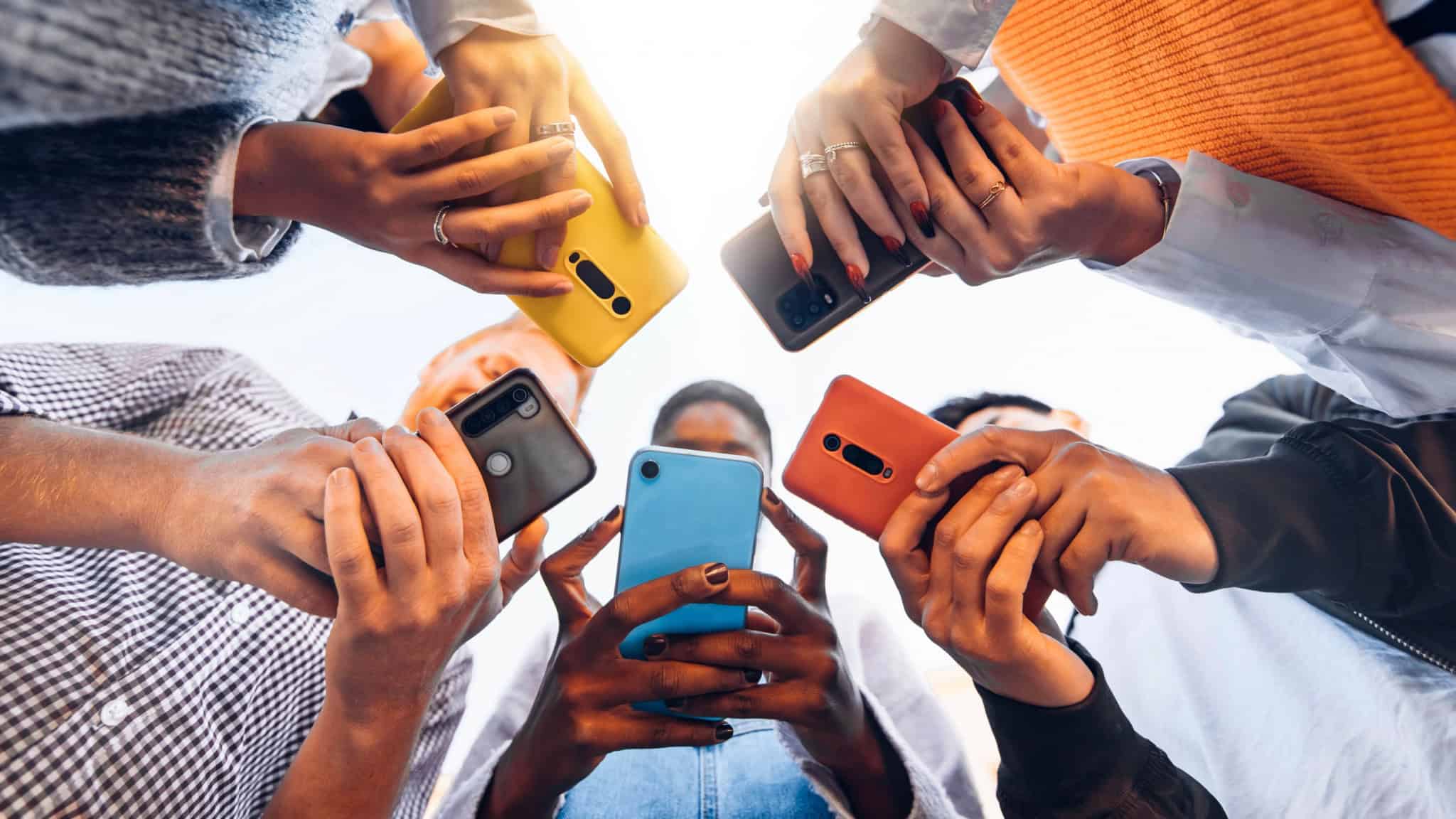 Foto de baixo para cima mostrando crianças usando smartphones