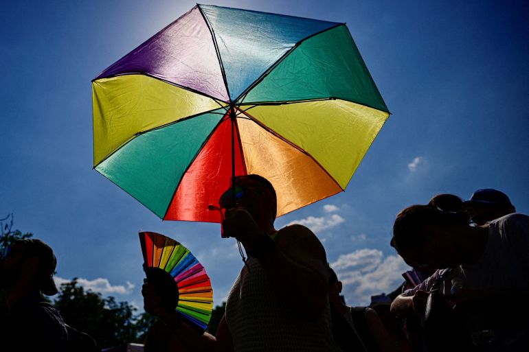 An umbrella in the colors of a Pride flag as people attend the Budapest Pride march