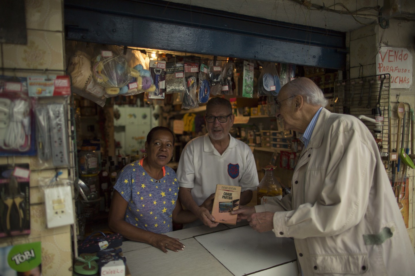 Zuenir Ventura e surpreendido por um casal dono de um bar com o exemplar autografado por ele em 1994. Zuenir Ventura, autor do livro Cidade Partida, revisita o local da chachina narrada na obra, em Vigario Geral — Foto: Daniel Marenco / Agencia O Globo