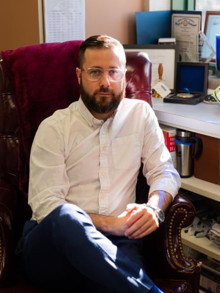 A younger man with a beard sitting in an office.