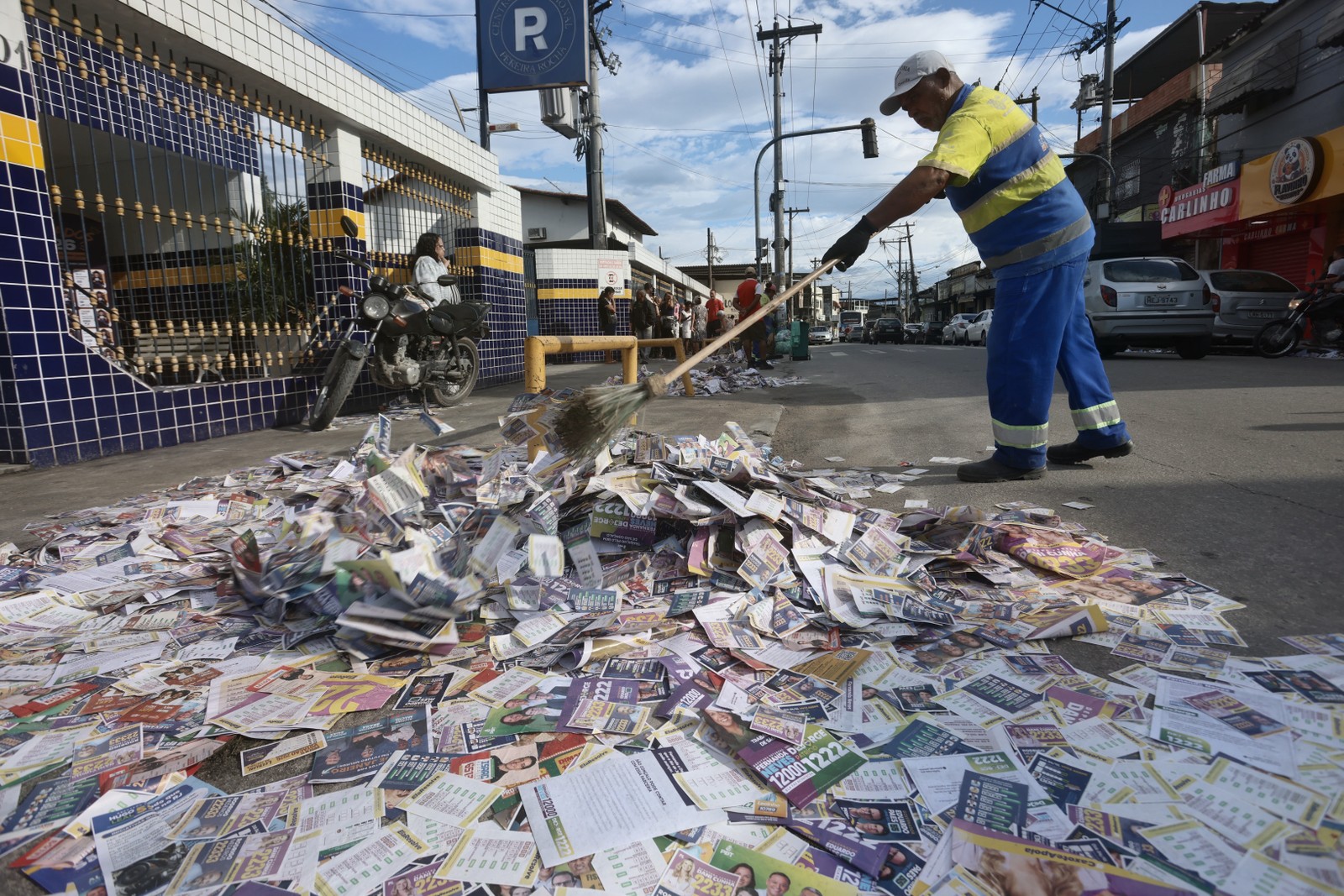 Limpeza de santinhos em frente ao Colégio Pereira Rocha, em São Gonçalo (RJ) — Foto: Fabiano Rocha / Agência O Globo