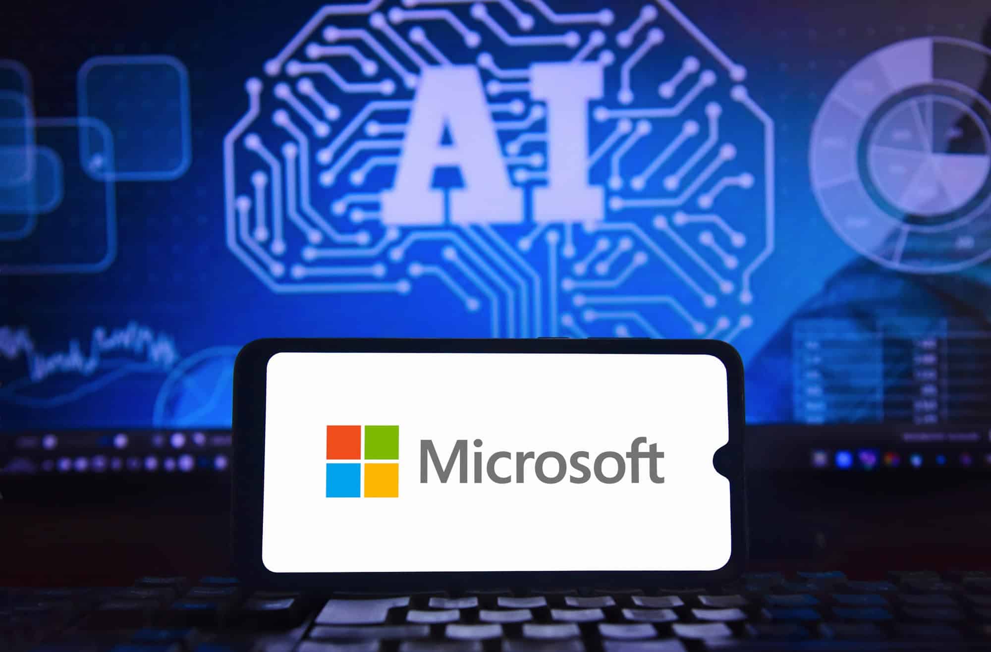 Logo da Microsoft exibido em um notebook diante de uma tela com elementos gráficos relacionados à inteligência artificial.